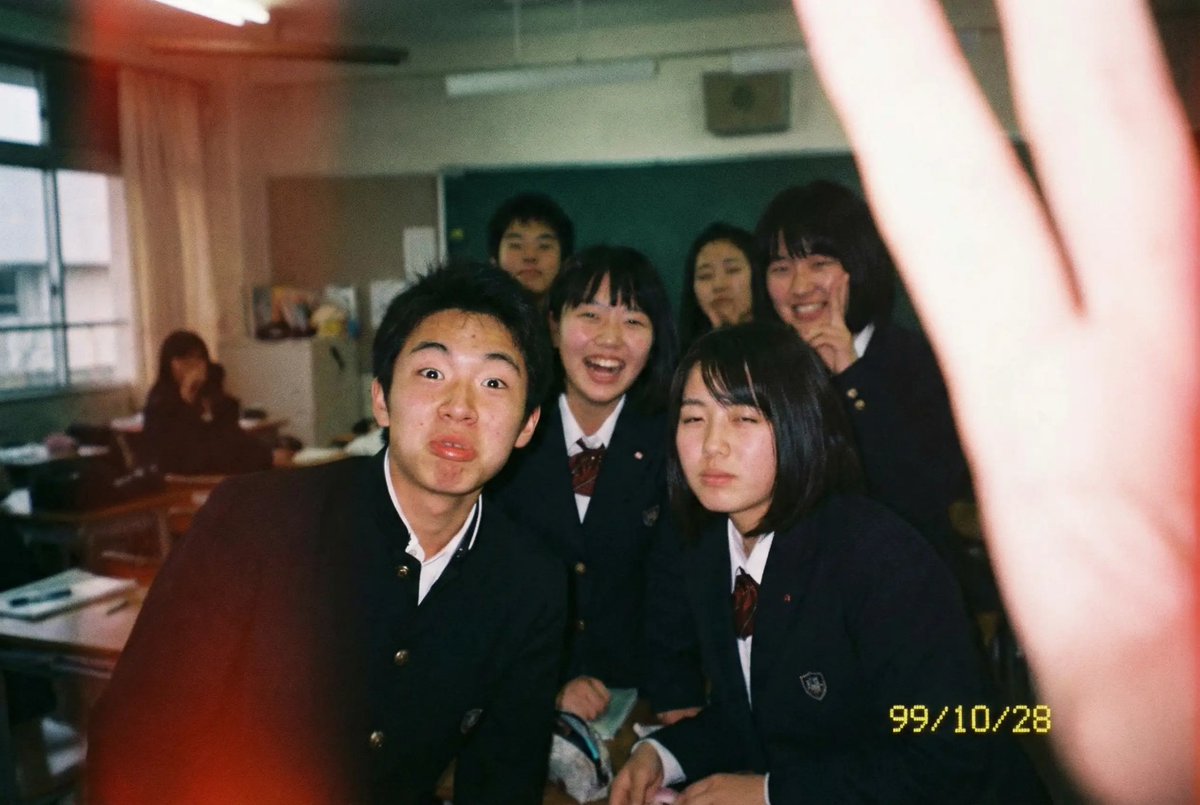 An everyday classroom snapshot taken with a disposable film camera, featuring natural film grain, authentic flash, and youthful school-life energy. I…